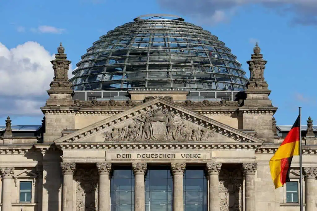 The reichstag building with glass dome and german flag.